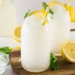 Lemonade slushie in a tall glass garnished with mint leaves and lemon sliced.