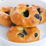 Blueberry bagels sitting on a white plate.