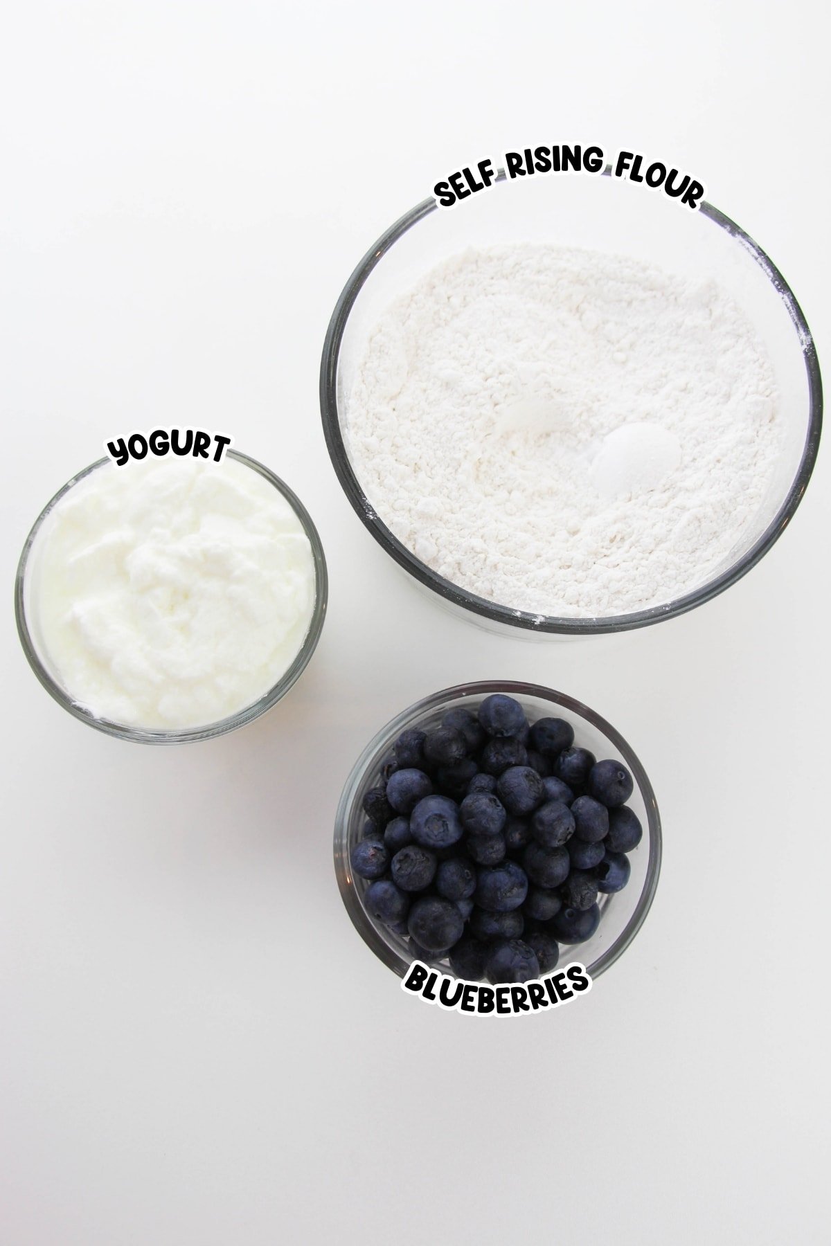 Flour, yogurt, and blueberries on a white countertop.