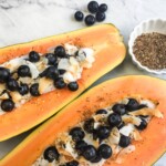Papaya Breakfast Bowls topped with blueberries, yogurt, and chia seeds.