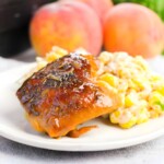 Peach BBQ chicken sitting on a white plate.