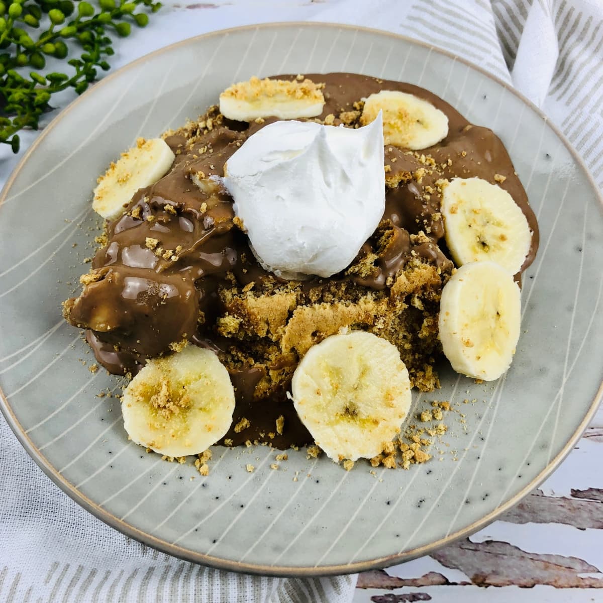 A plate of chocolate banana icebox cake garnished with six slices of bananas topped with whipped cream.