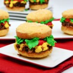 Whoopie pie decorated with frosting to look like a burger with cheese, tomato, and lettuce.
