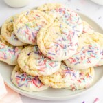 A pile of cookies with melted vanilla wafers and sprinkles sitting on a white plate.