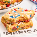 Two stacks of M&M cookie bars with one bite missing.