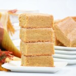 Four churro bars stack together sitting on a white plate.