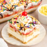 Slice of banana split dessert sitting on a small, white plate.