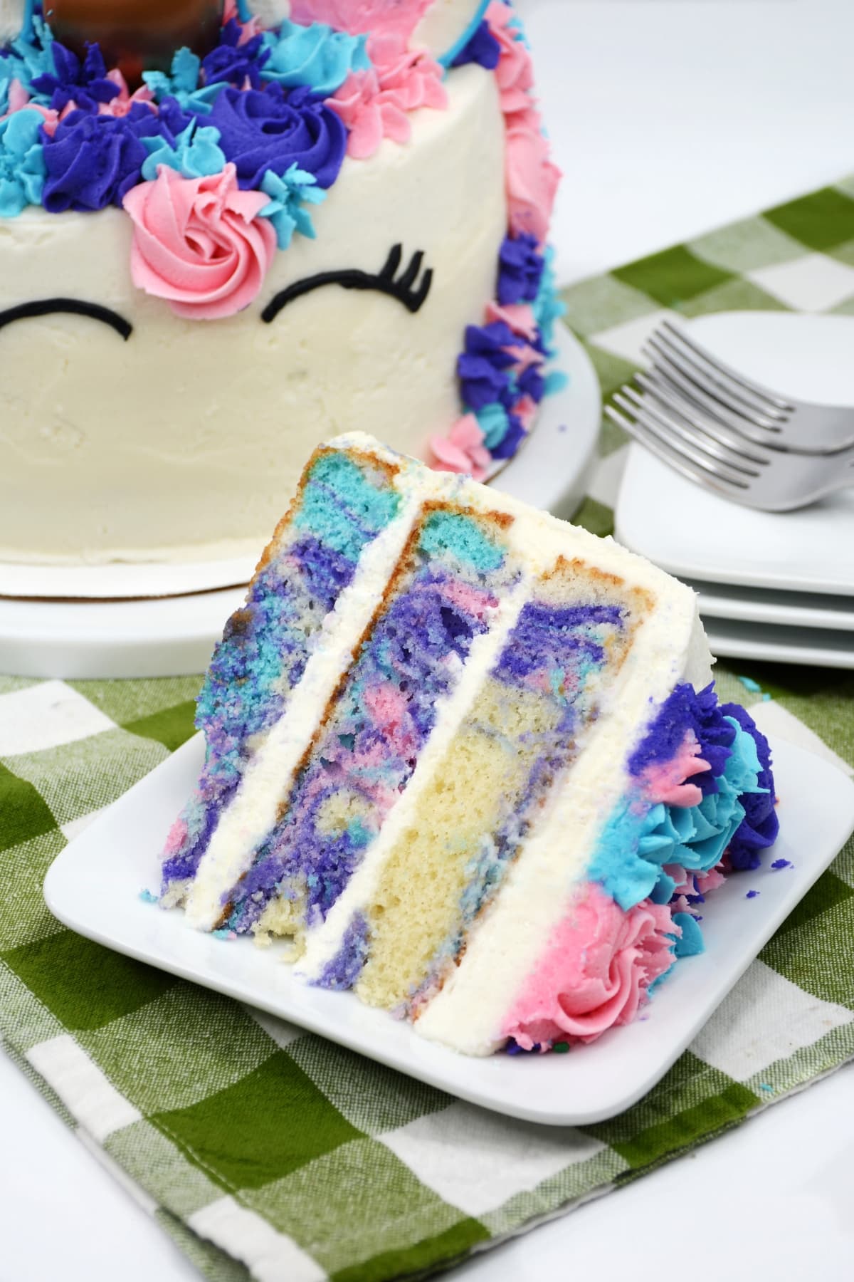 A white plate with a slice of unicorn themed cake.
