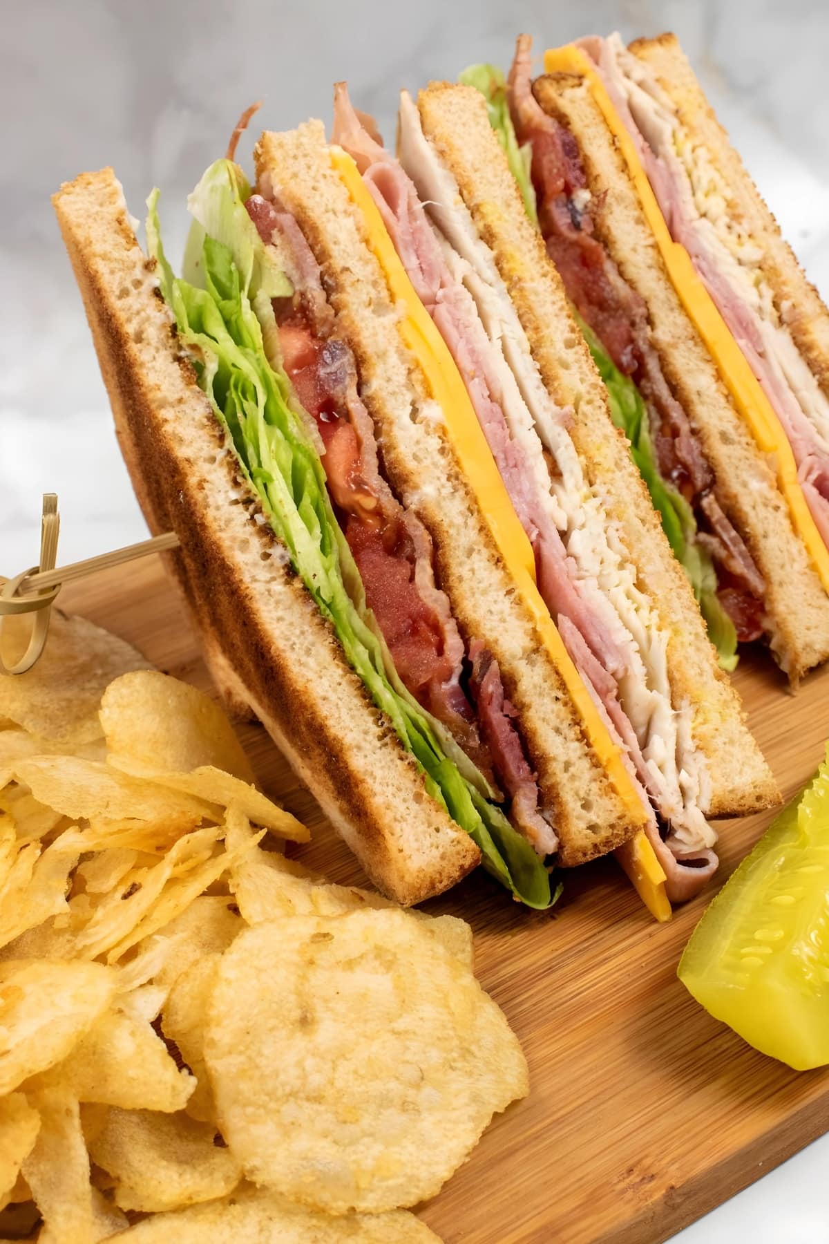 A slice of a club sandwich with chips on the side.