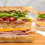 Club Sandwich with a toothpick on a wooden board.
