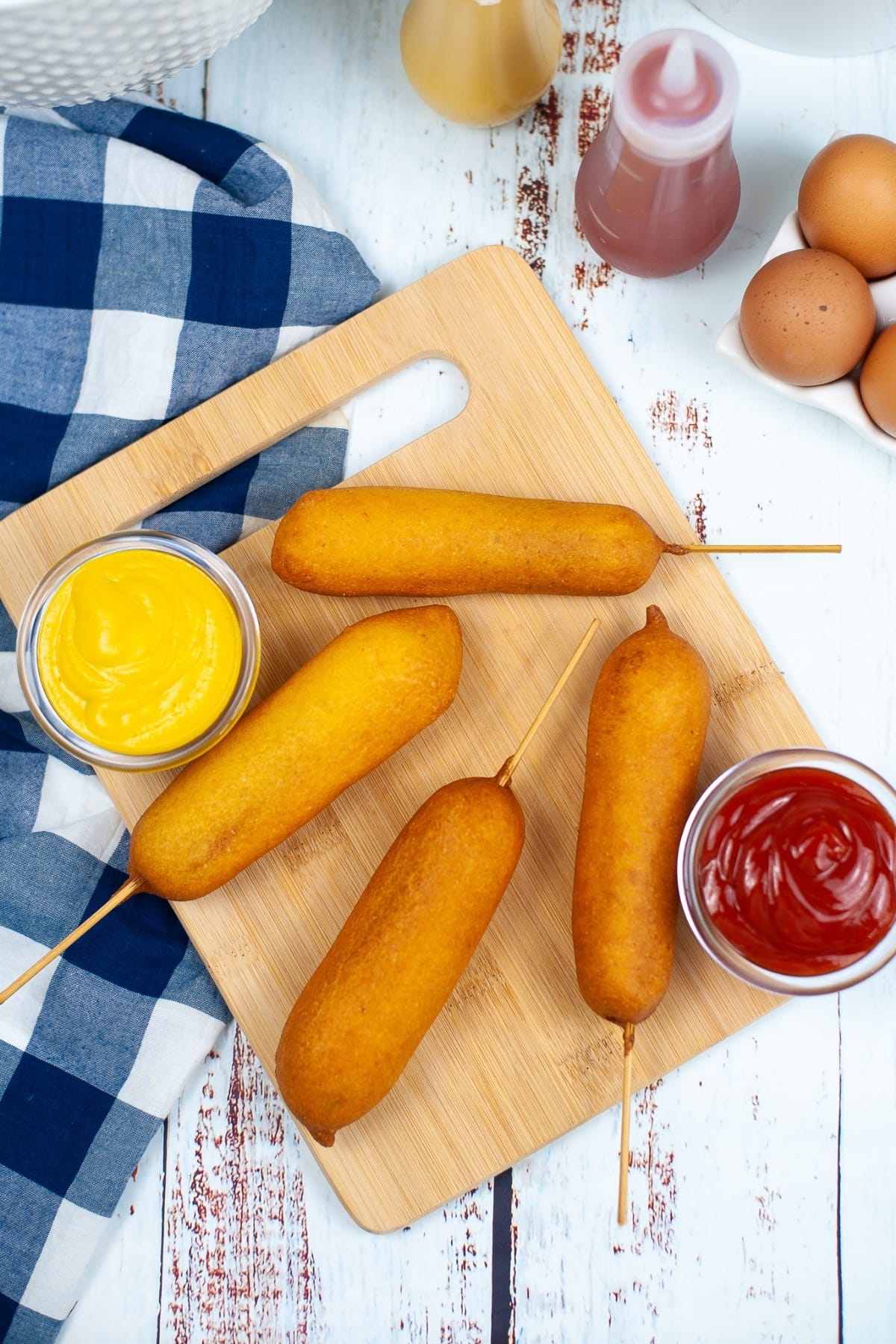 Corn Dogs with ketchup and mustard on the sides.