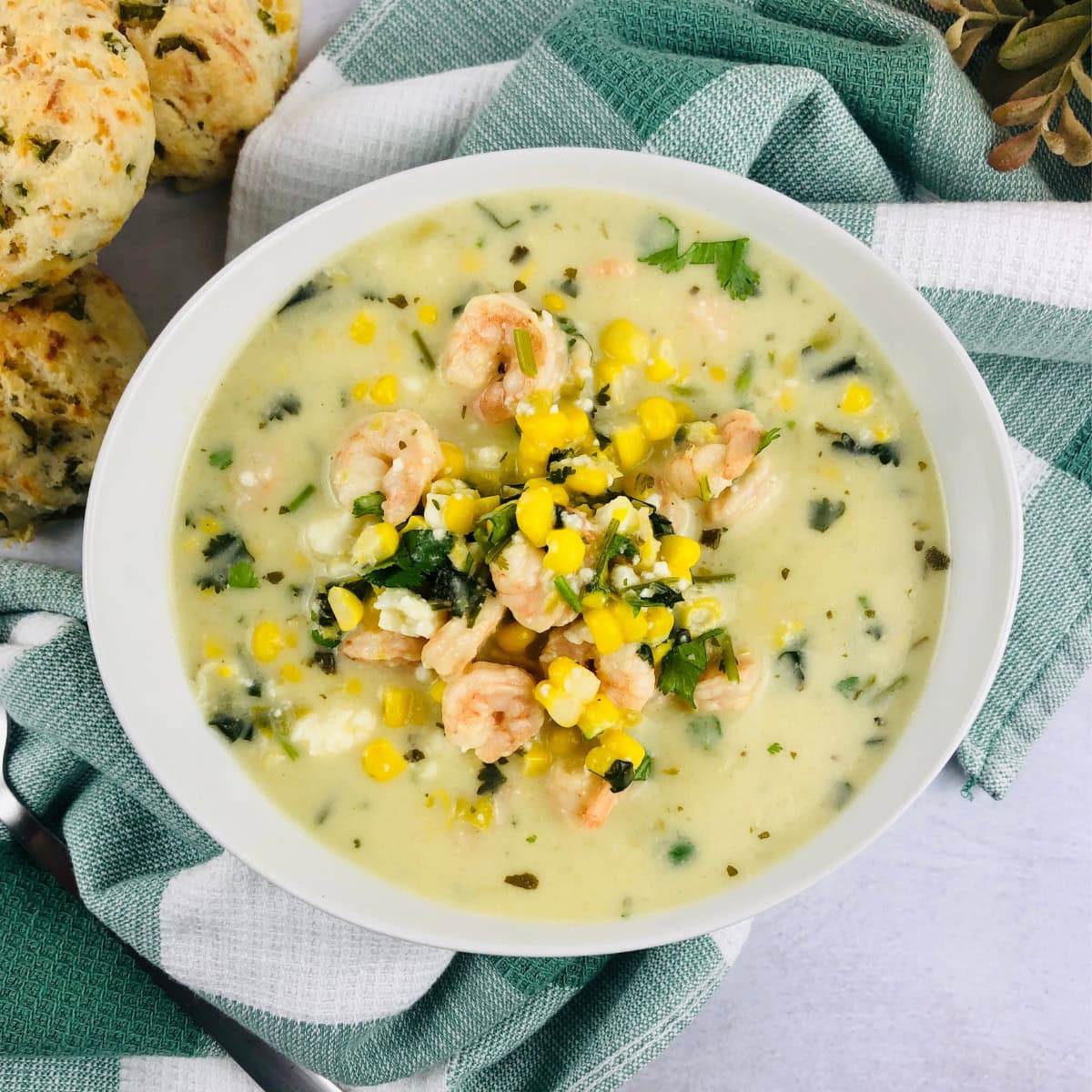 White bowl of Green Chile Corn Chowder with scones on the side.