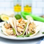Cilantro lime shrimp in a tacos sitting on a white plate.