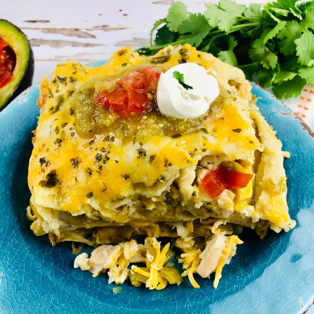 Blue plate with green chile Chicken Enchilada casserole.