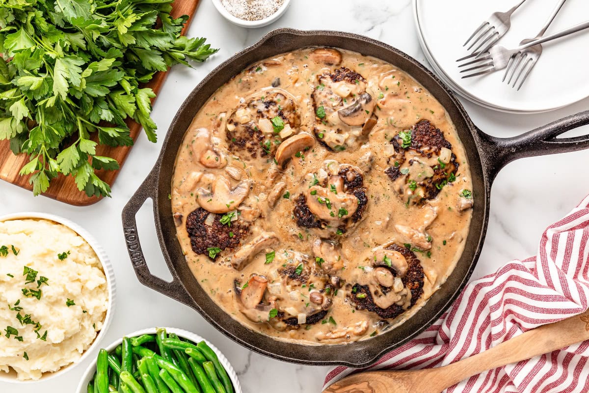 Hamburger-Steaks in a cast iron pan.