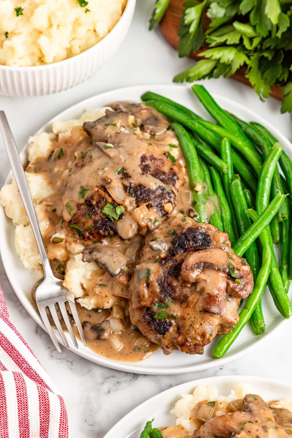 Hamburger steak with mushroom gravy on top of mashed potato.
