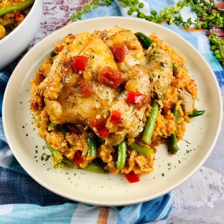 Chicken thighs with creamy sauce on top of rice with green beans.