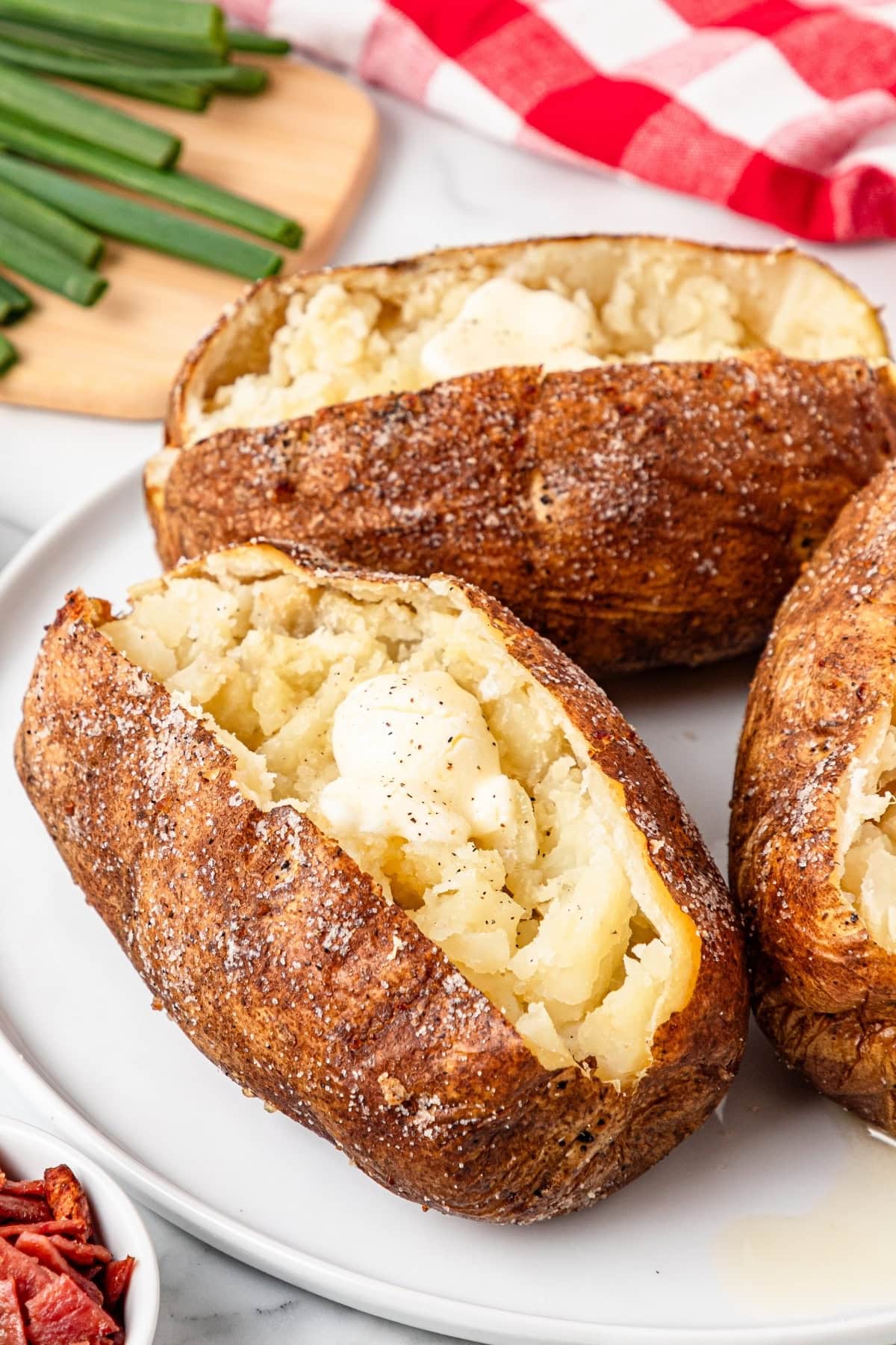 A white plate with baked potatoes topped with butter.