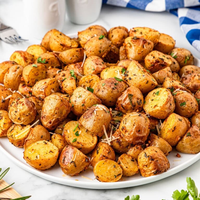 A white plate of Roasted Baby Potatoes garnished with parmesan.