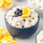 Blueberry salad in a blue bowl topped with blueberries and a slice of lemon.
