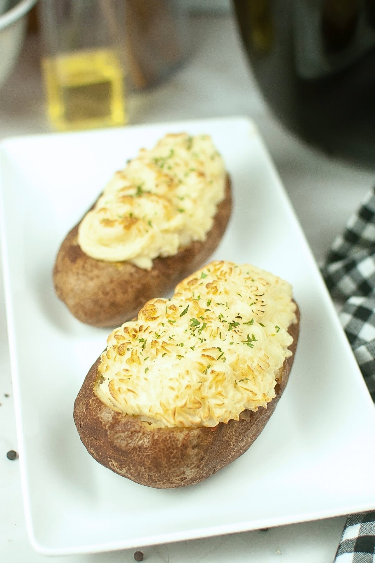 A white plate of potatoes stuffed with meat and veggies and topped with mashed potatoes.