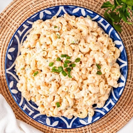 A blue plate of Macaroni Hawaiian Salad with Celery and carrots on the sides.