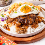 Hamburger patty with gravy topped with egg on a bed of rice.