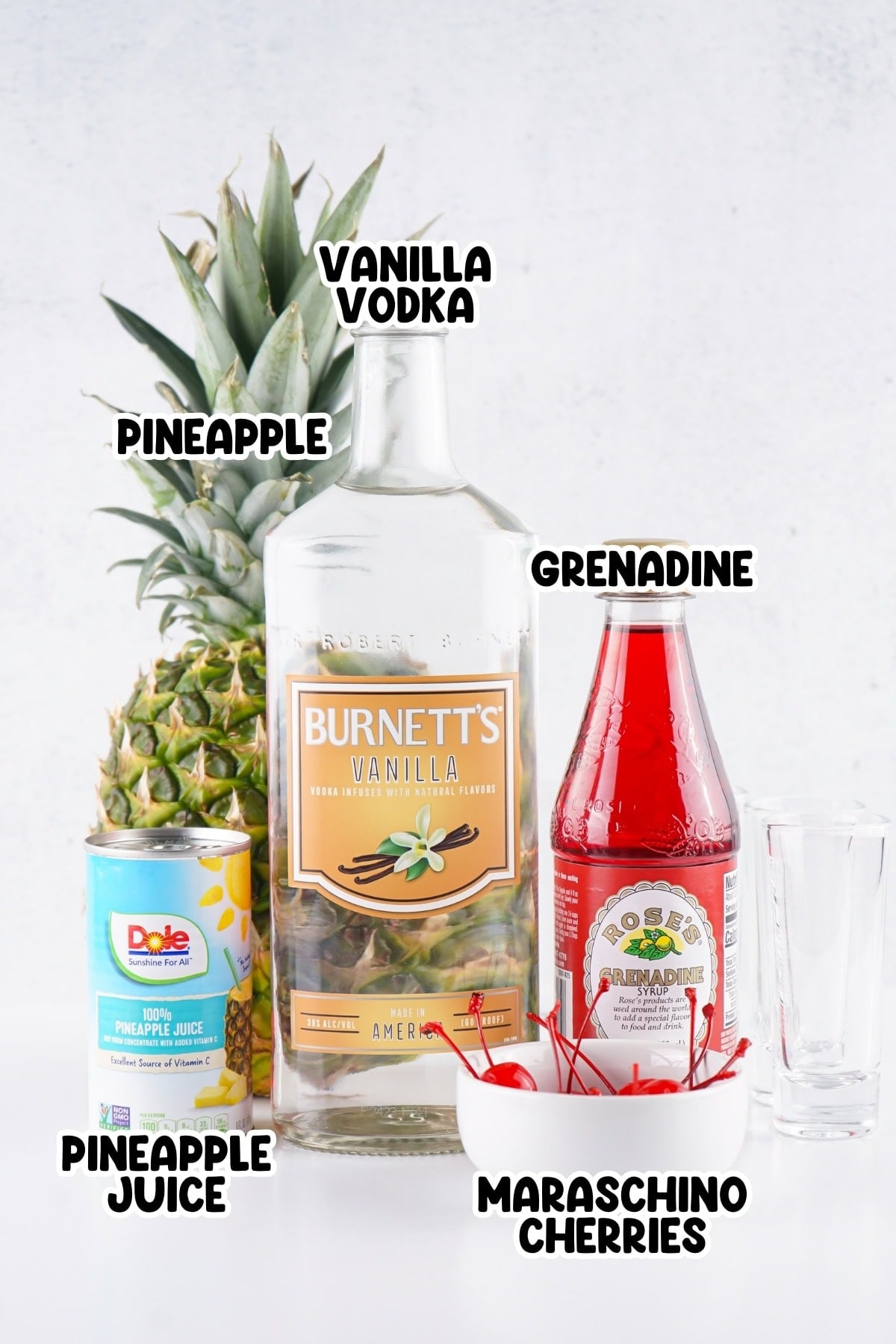 Ingredients of pineapple vodka shots sitting on a white countertop.