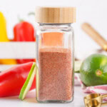 Tajin seasoning in an air tight container sitting on a white countertop.