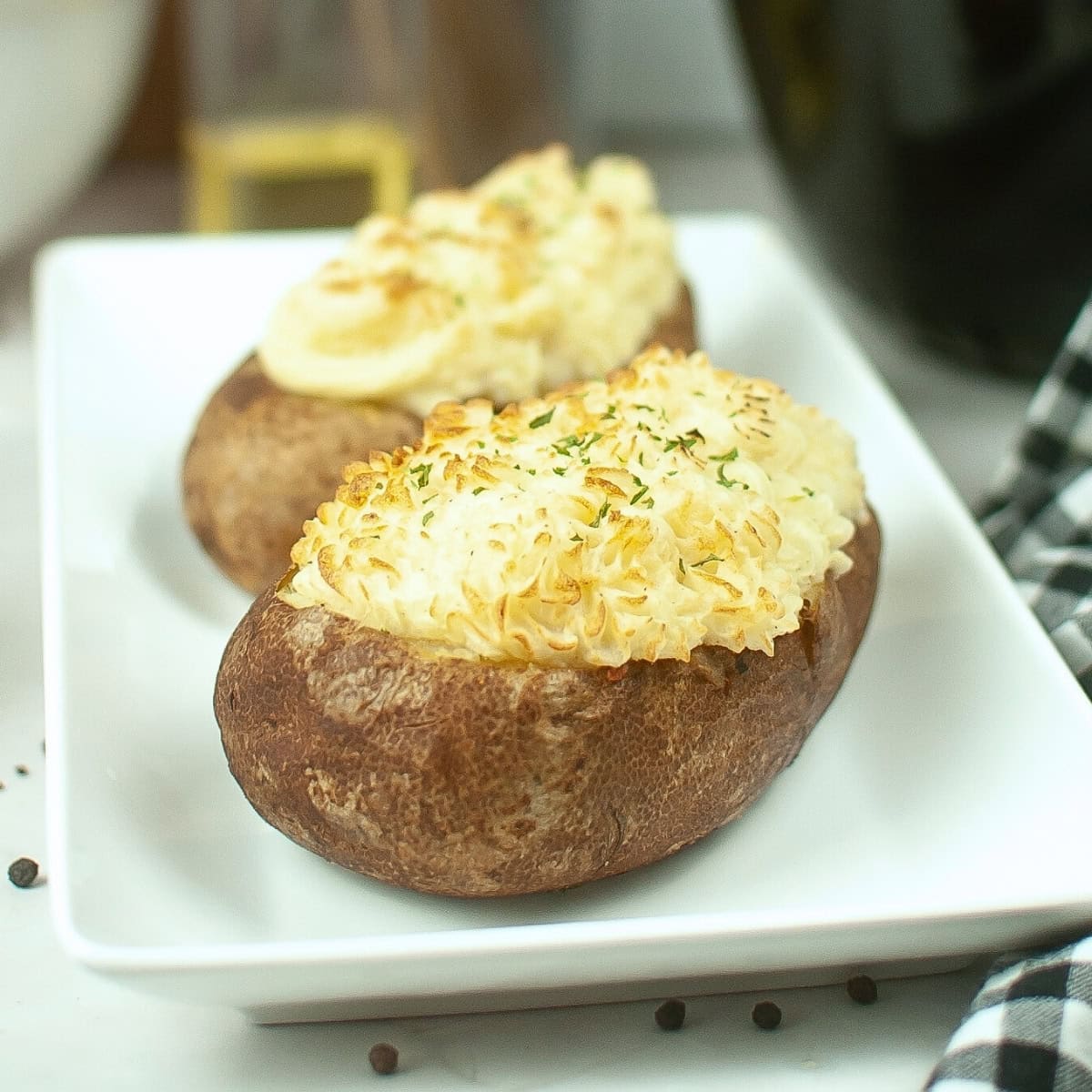 A plate of baked potatoes stuffed with meat and veggie mixture.