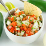 A white plate of pico de gallo with one chip on top.