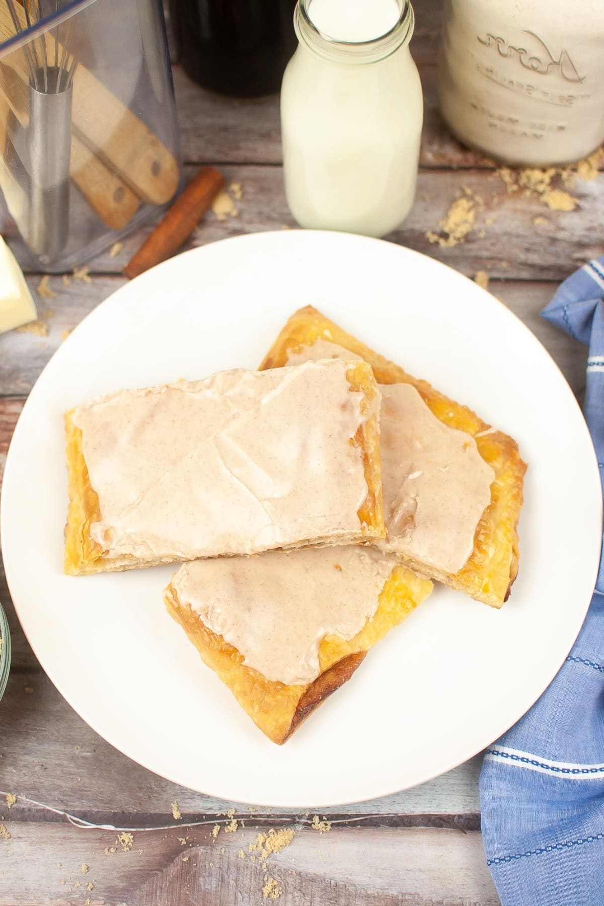 Three pop tarts with powdered sugar and cinnamon mixture icing on a white plate.