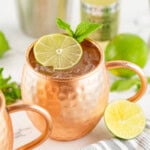 Moscow mule in a mug with ice topped with a slice of lime and mint.