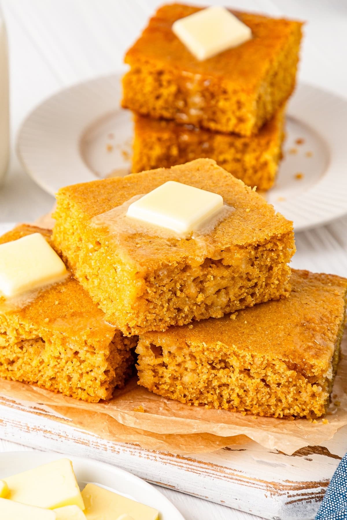 Slices of sweet cornbread with small slices of butter on top.
