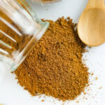 Chinese 5 Spice Powder in a glass container spilled on a countertop.