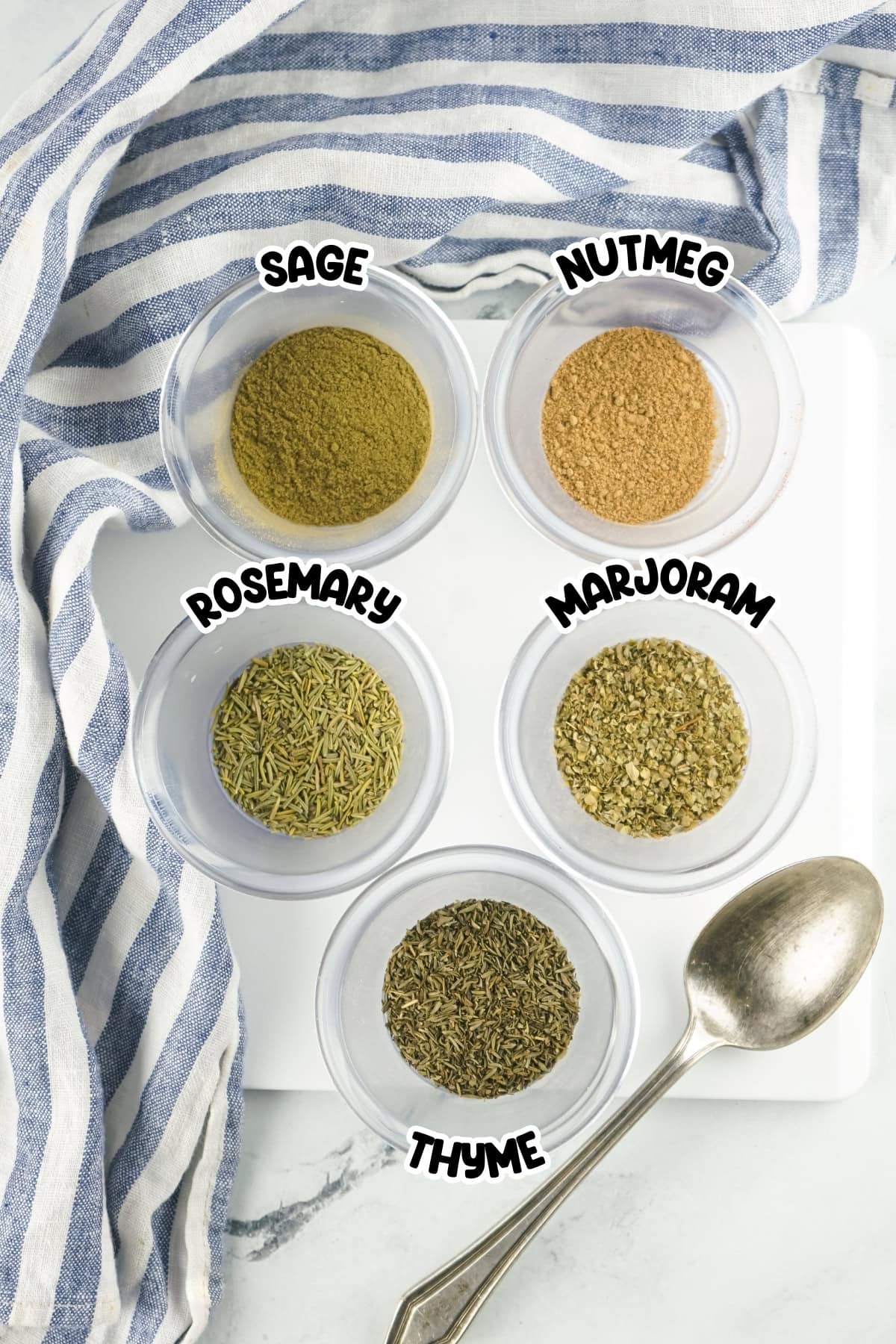 Ingredients for poultry seasoning sitting on a white countertop.