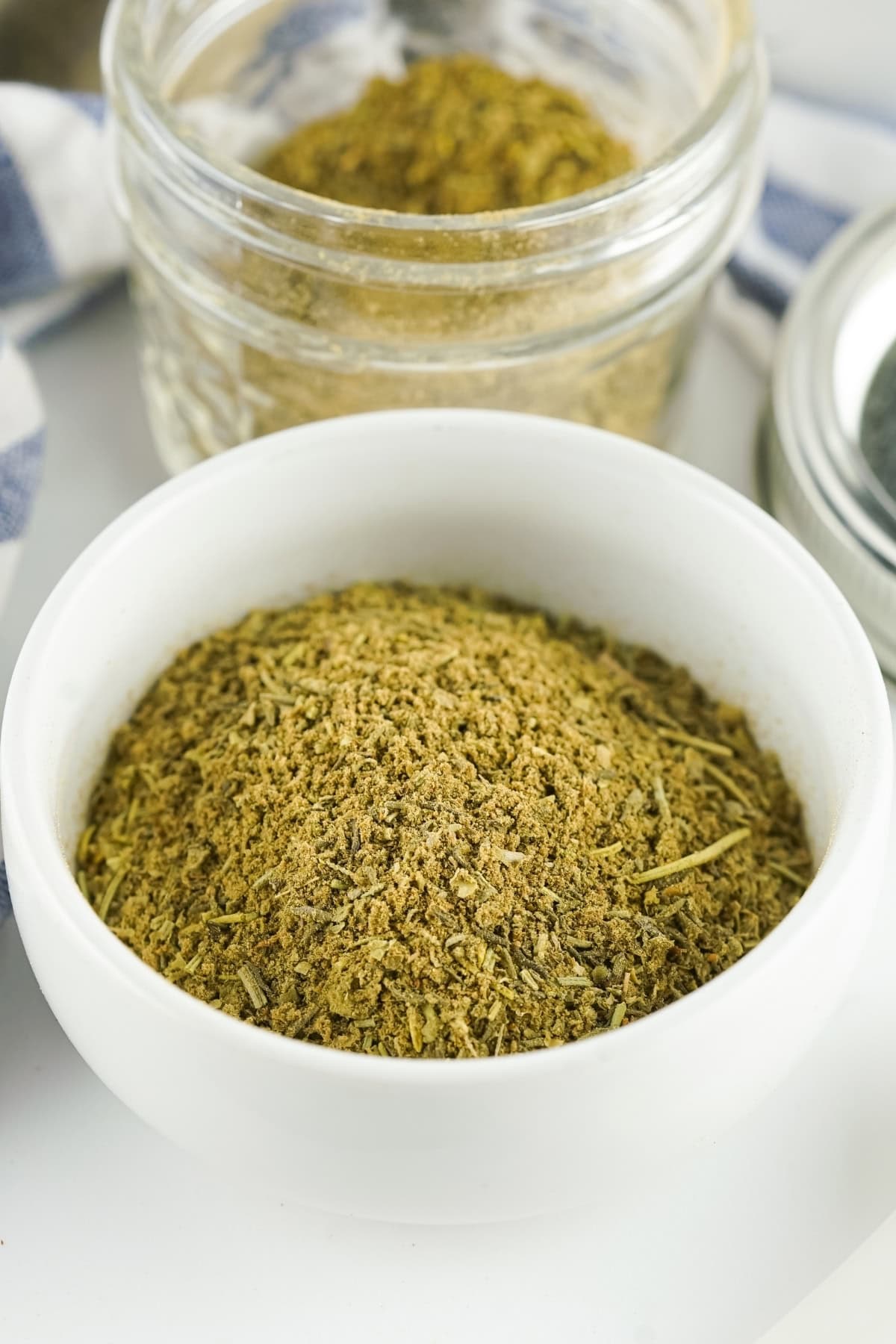 Poultry seasoning in a white bowl sitting on a white countertop.