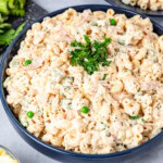 A blue plate of tuna macaroni salad with chopped parsley on top.