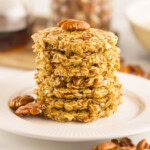 A white plate with a pile of cookies made of oats, maple syrup, and chopped pecans.