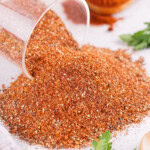 An airtight container with BBQ Dry Rub spilled on a white countertop.