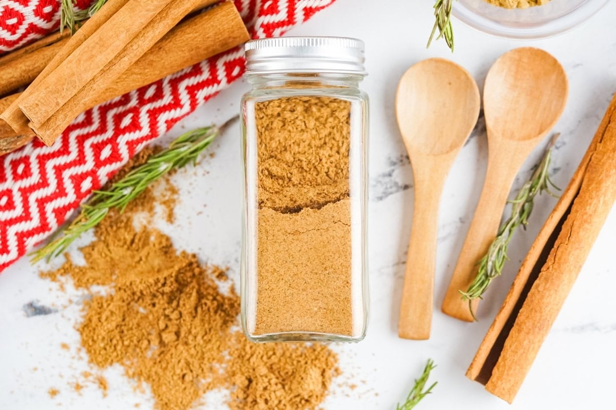 Gingerbread Spice mix in an airtight container sitting on a marbled countertop.