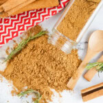 Gingerbread Spice mix spilled on a marbled countertop with a wooden spoon on the side.