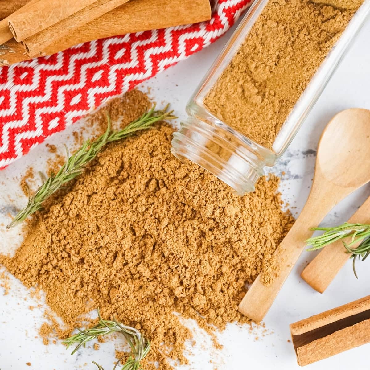 Gingerbread Spice mix spilled on a marbled countertop with a wooden spoon on the side.