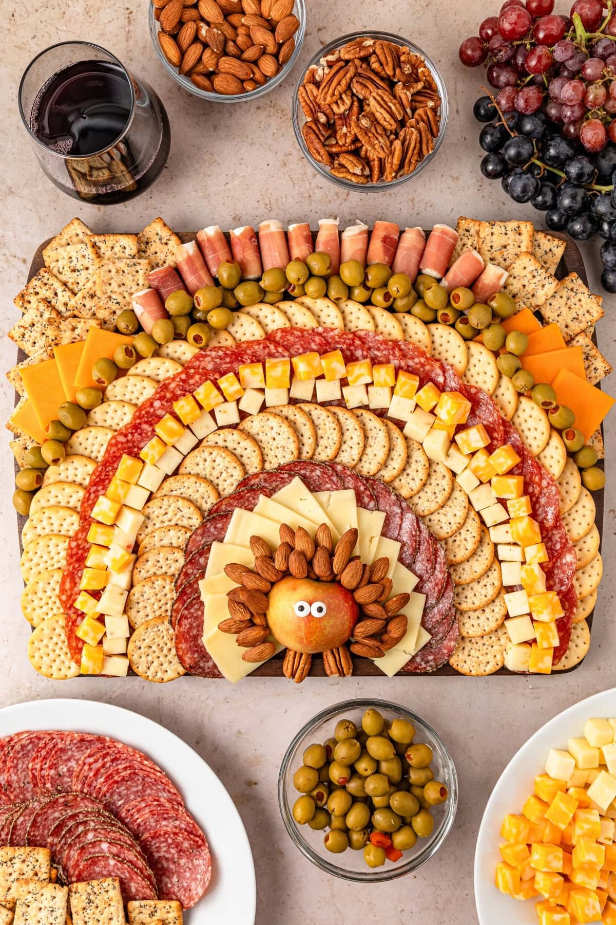 Charcuterie board with almonds, crackers, different kinds of cheeses, salami, Prosciutto and olives.