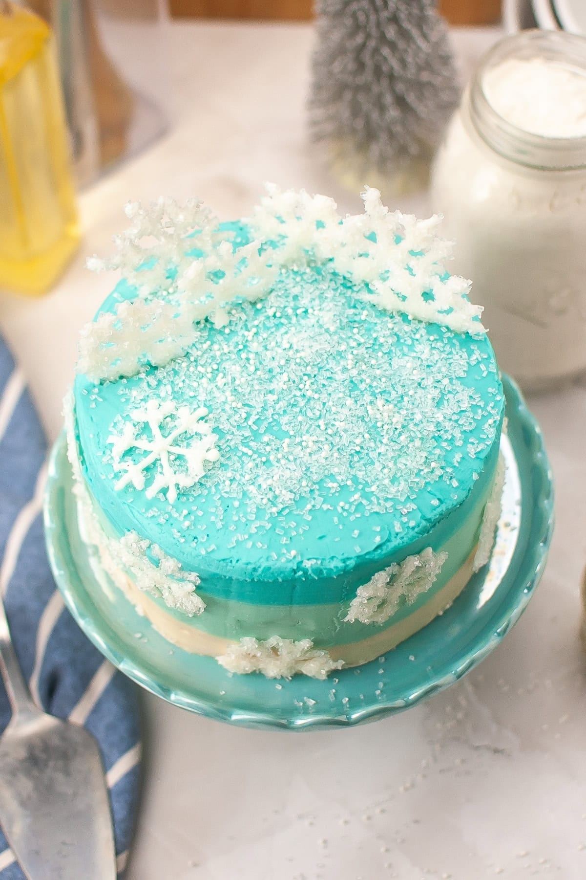 Blue Winter wonderland cake with white snowflake decorations on a plate.