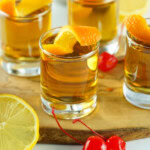 Shot glasses with Three Wise Men drink, garnished with orange peels.