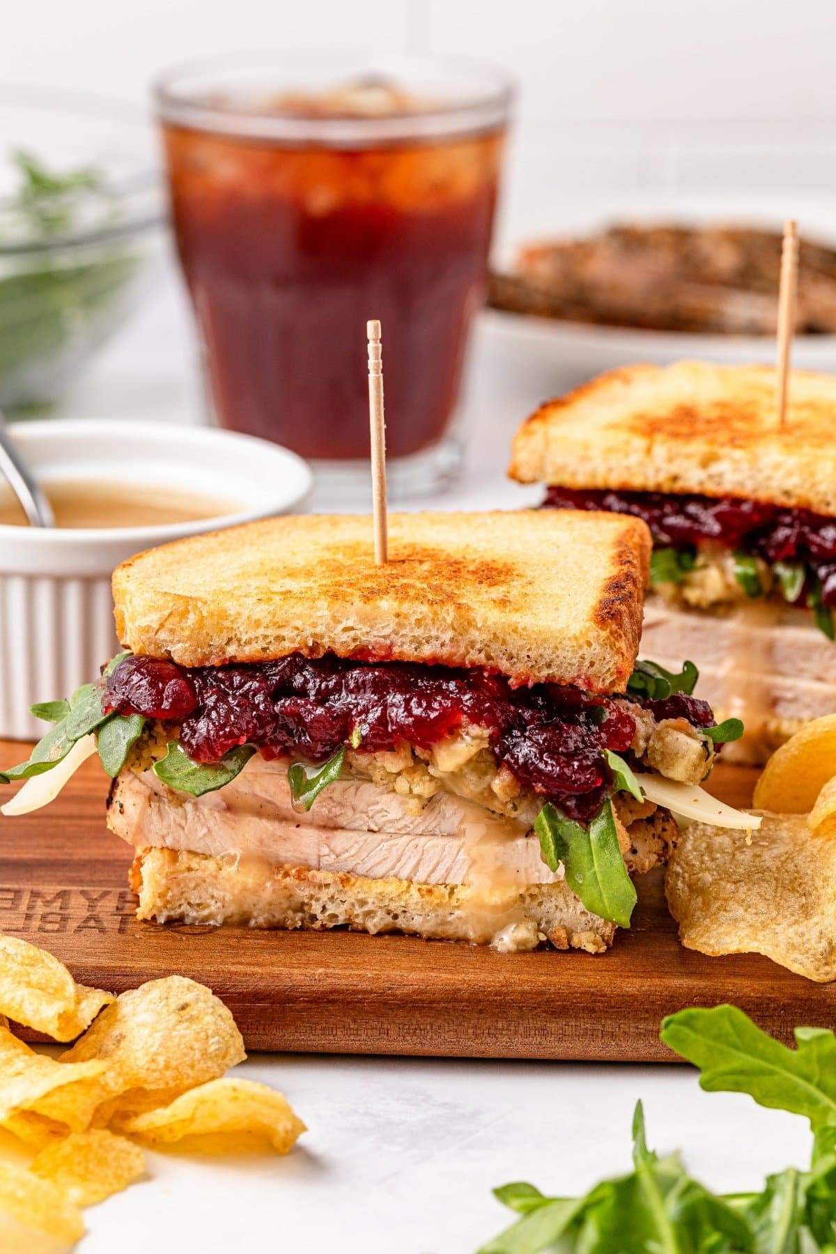 Turkey sandwich with cranberry sauce and arugula on a wooden board.