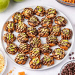 Plate of caramel apple bites drizzled with chocolate and topped with nuts.