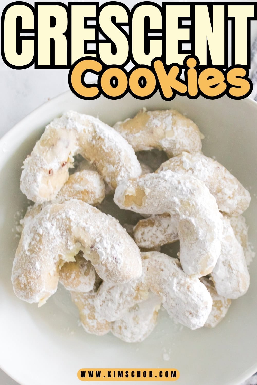 Powdered crescent cookies piled on a white plate.