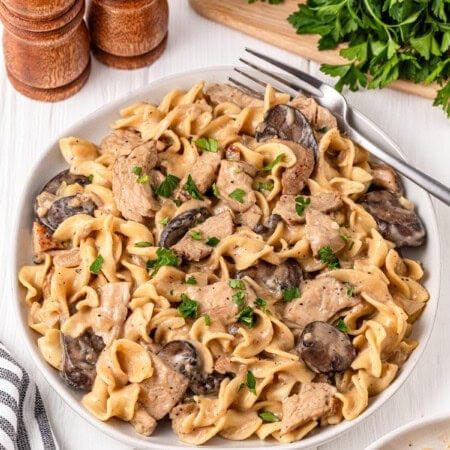 A plate of creamy mushroom pasta with herbs.